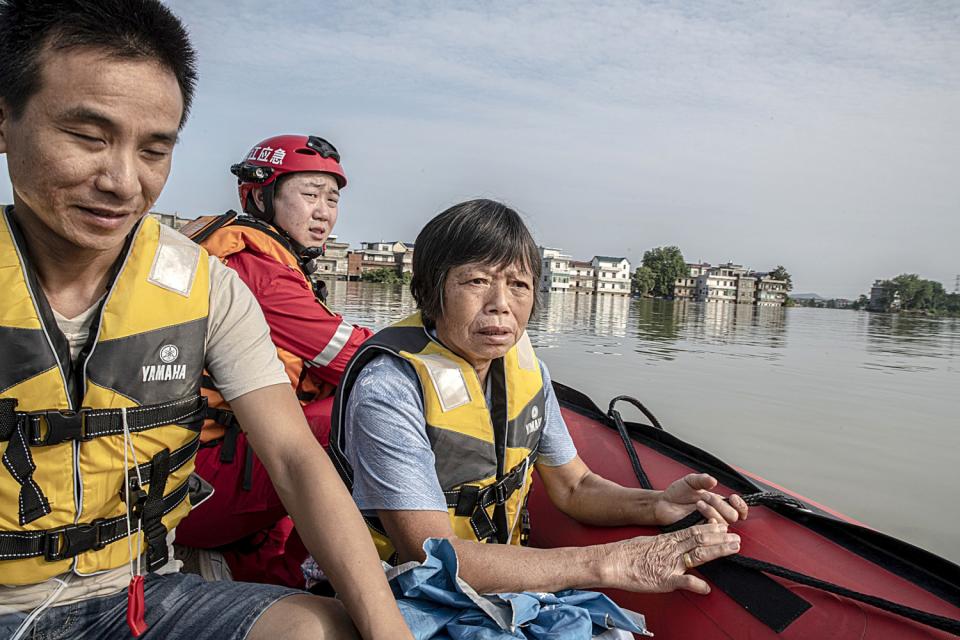 Zhang Meifeng and son-in-law Gao return to their flooded home on a rescue boat.