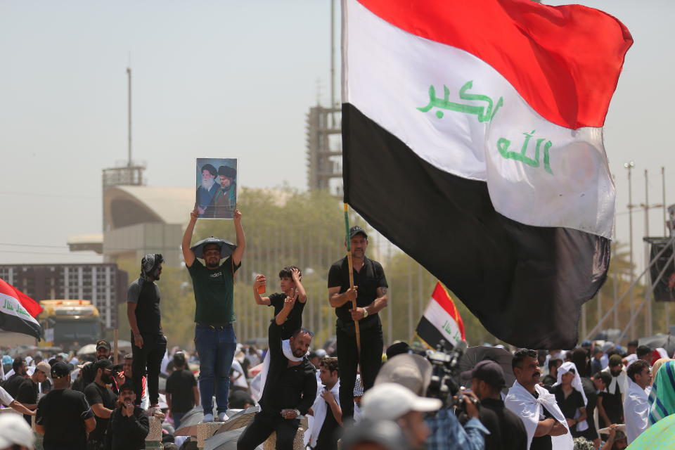 Followers of Shiite cleric Muqtada al-Sadr hold posters with his image during an open-air Friday prayers at Grand Festivities Square within the Green Zone, in Baghdad, Iraq, Friday, Aug. 5, 2022. (AP Photo/Anmar Khalil)