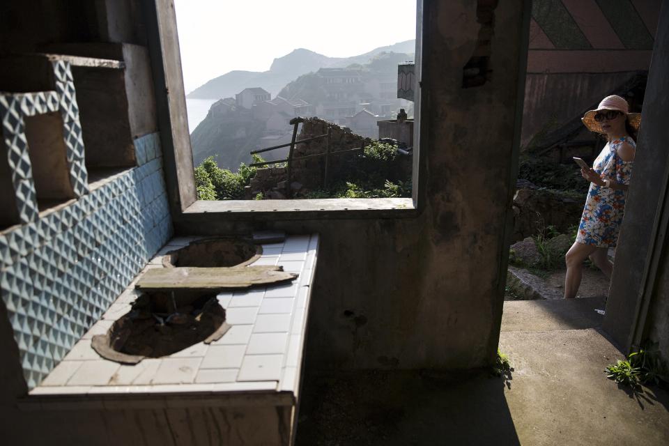 A tourist looks inside a house in the abandoned fishing village of Houtouwan on the island of Shengshan July 26, 2015. (REUTERS/Damir Sagolj)