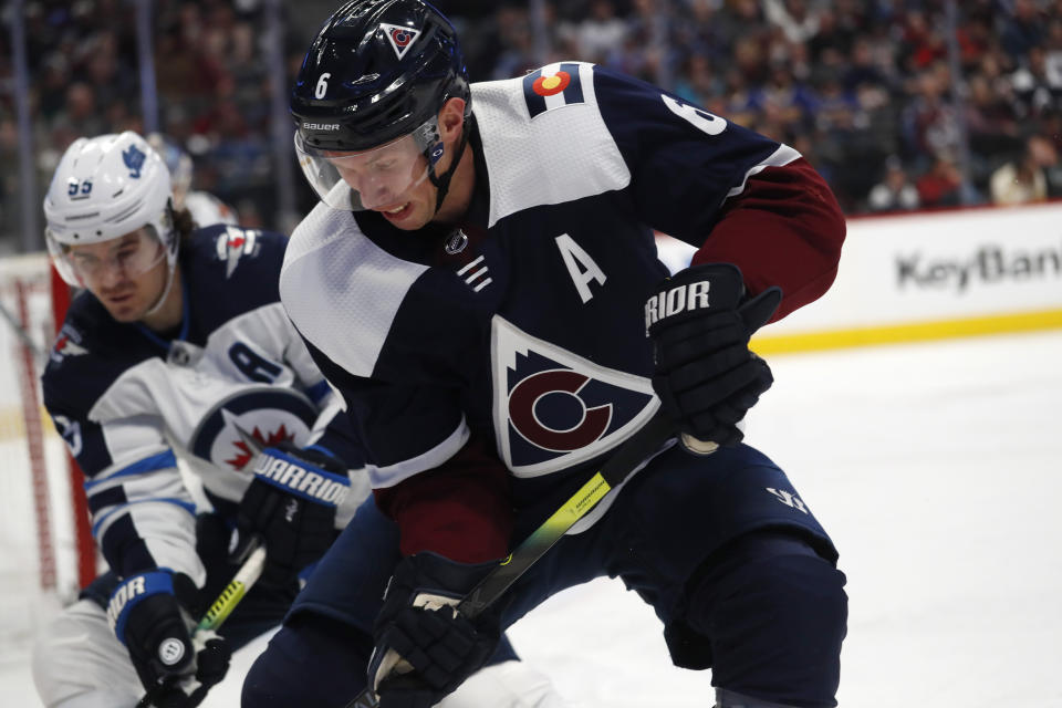 Colorado Avalanche defenseman Erik Johnson, front, fights for control of the puck in the corner with Winnipeg Jets center Mark Scheifele during the second period of an NHL hockey game Tuesday, Dec. 31, 2019, in Denver. (AP Photo/David Zalubowski)