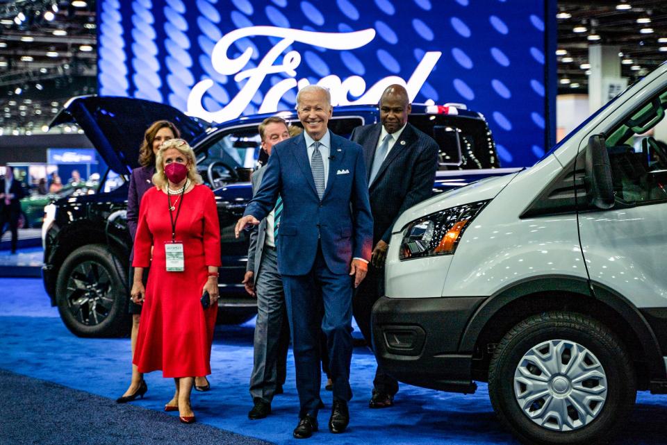 President Joe Biden smiles at the media while touring the 2022 North American International Auto Show flanked by local officials at Huntington Place in downtown Detroit on Wed., Sept. 14, 2022