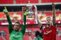 Arsenal's goalkeeper Lukasz Fabianski (L) and Per Mertesacker lift the trophy to celebrate their victory against Hull City in their FA Cup final at Wembley Stadium in London, May 17, 2014. REUTERS/Darren Staples