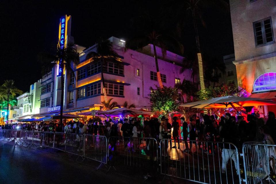 People walk along the sidewalk on Ocean Drive during spring break in Miami Beach on Friday, March 15, 2024.