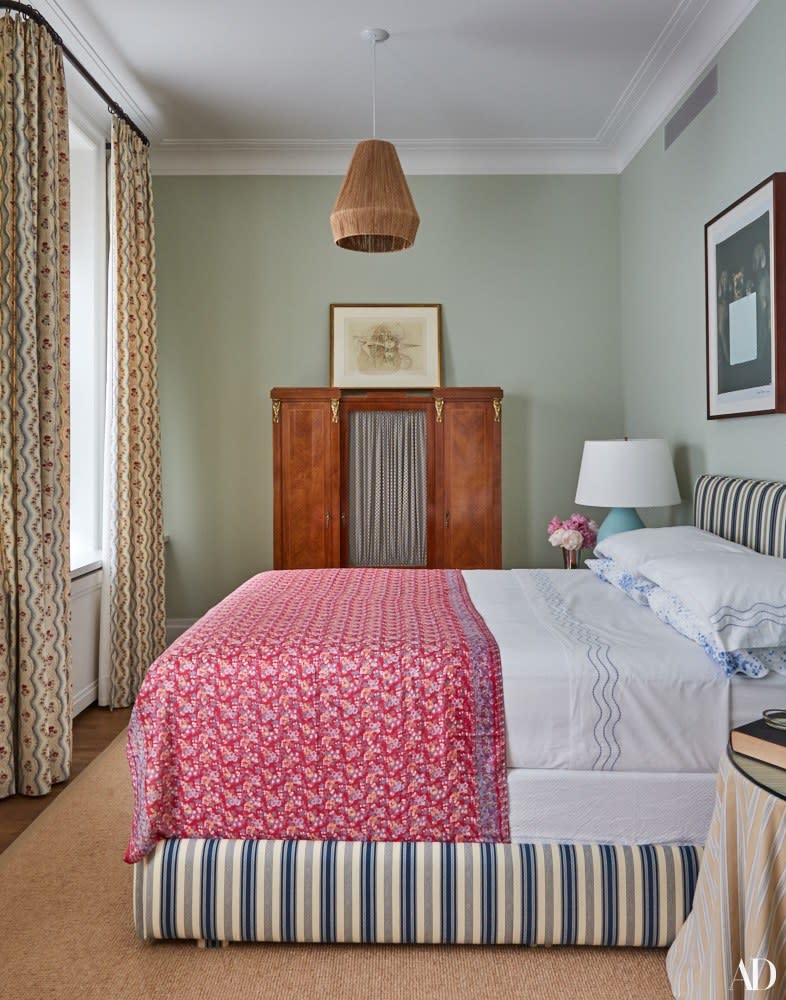 A custom guest bed is dressed in a Le Manach cotton, D. Porthault linens, and an antique sari as a throw. On walls, Galt Blue paint by Benjamin Moore; 19th-century rosewood cabinet; rug by Crosby Street Studios.