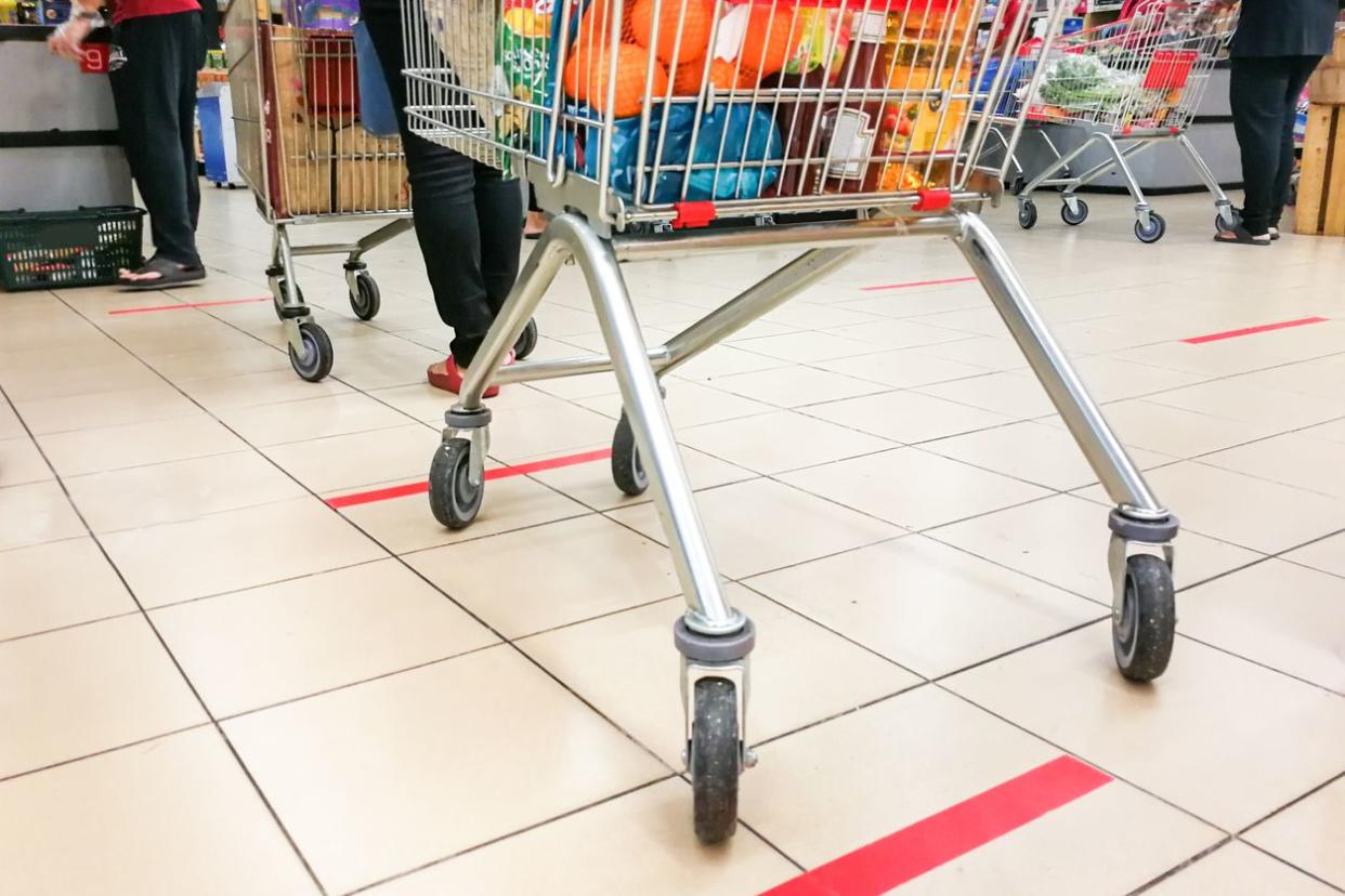 View of floor at supermarket showing customers legs and carts while waiting to check out.