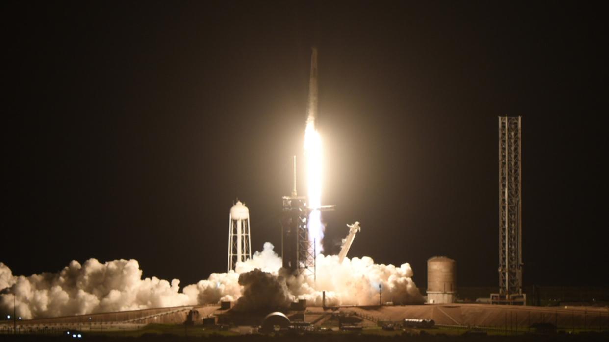  A rocket launches at night above a large plume of fire. 