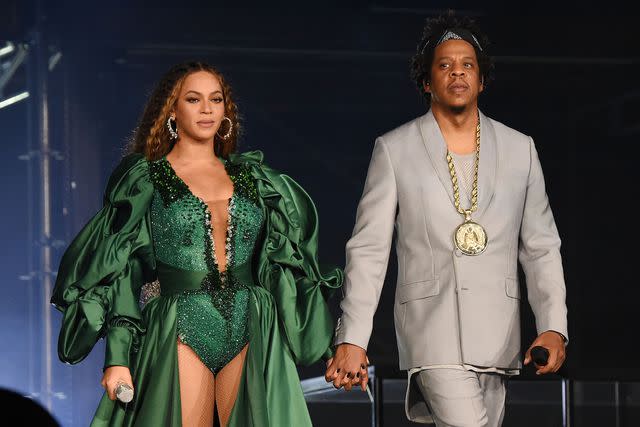 <p>Kevin Mazur/Getty</p> Beyoncé and Jay-Z holding hands on stage