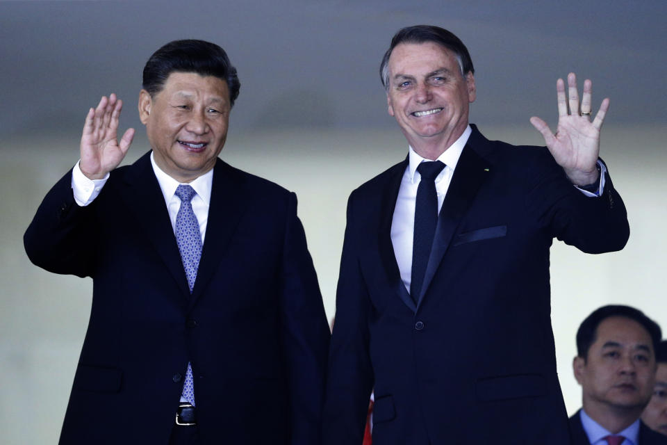 El presidente chino Xi Jinping, izquierda, y el brasileño Jair Bolsonaro saludan a la prensa al arribo de Xi a Brasil para la 11ma cumbre del BRICS, en el Palacio de Itamaraty, Brasilia, miércoles 13 de noviembre de 2019. (AP Foto/Eraldo Peres)