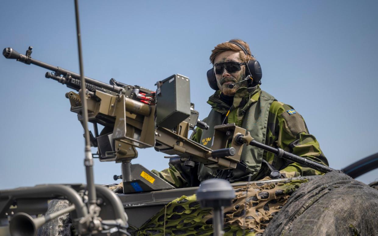 A Swedish soldier sits on a military boat with a machine gun during Nato drills