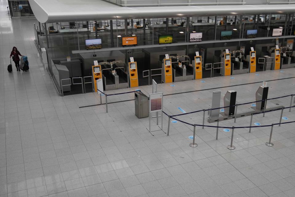 A woman passes the deserted departure terminal during a strike in Bavaria at the airport in Munich, Germany, Sunday, March 26, 2023. An increased number of travelers in Germany boarded trains and planes on Sunday to avoid a massive one-day strike Monday that's supposed to bring the country's transport system to a standstill. But even advance travels were met with disruptions in some places as Munich airport already shut down Sunday due to the strike and technical problems at Lufthansa in Frankfurt led to flight delays and cancellations at the country's biggest airport. (AP Photo/Matthias Schrader)