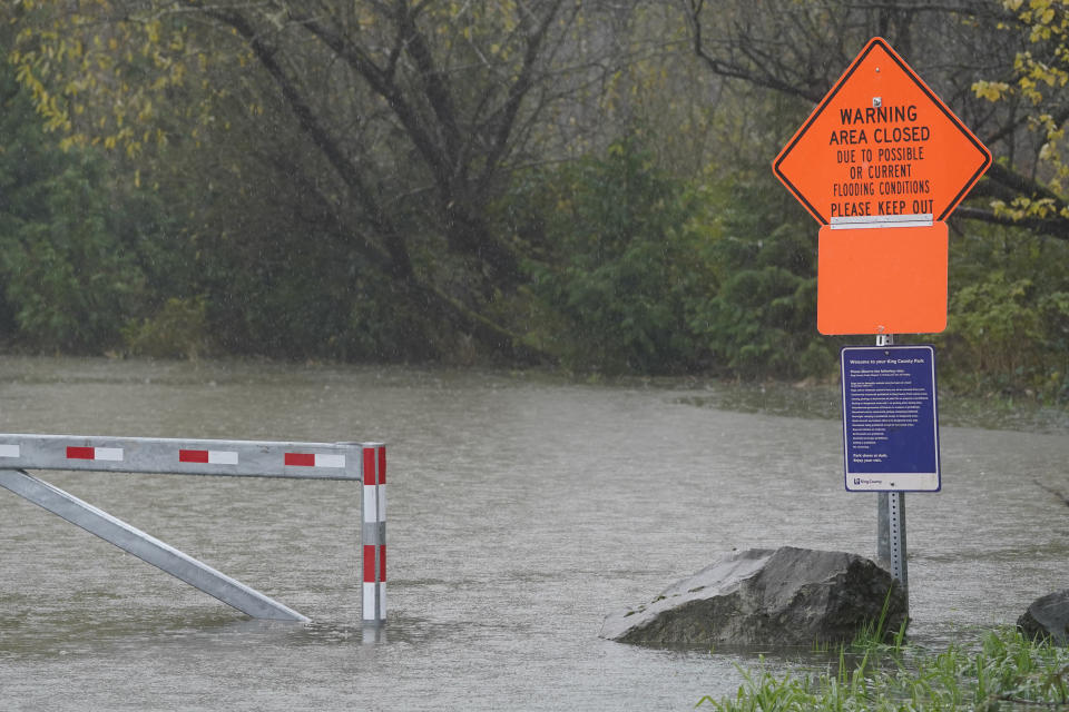 A sign warning of flooding conditions near an entrance to Tolt MacDonald Park is shown under water, Friday, Nov. 12, 2021, as rain falls near Carnation, Wash. Forecasters said the storms are being caused by an atmospheric river, known as the Pineapple Express and rain was expected to remain heavy in Oregon and Washington through Friday night. (AP Photo/Ted S. Warren)