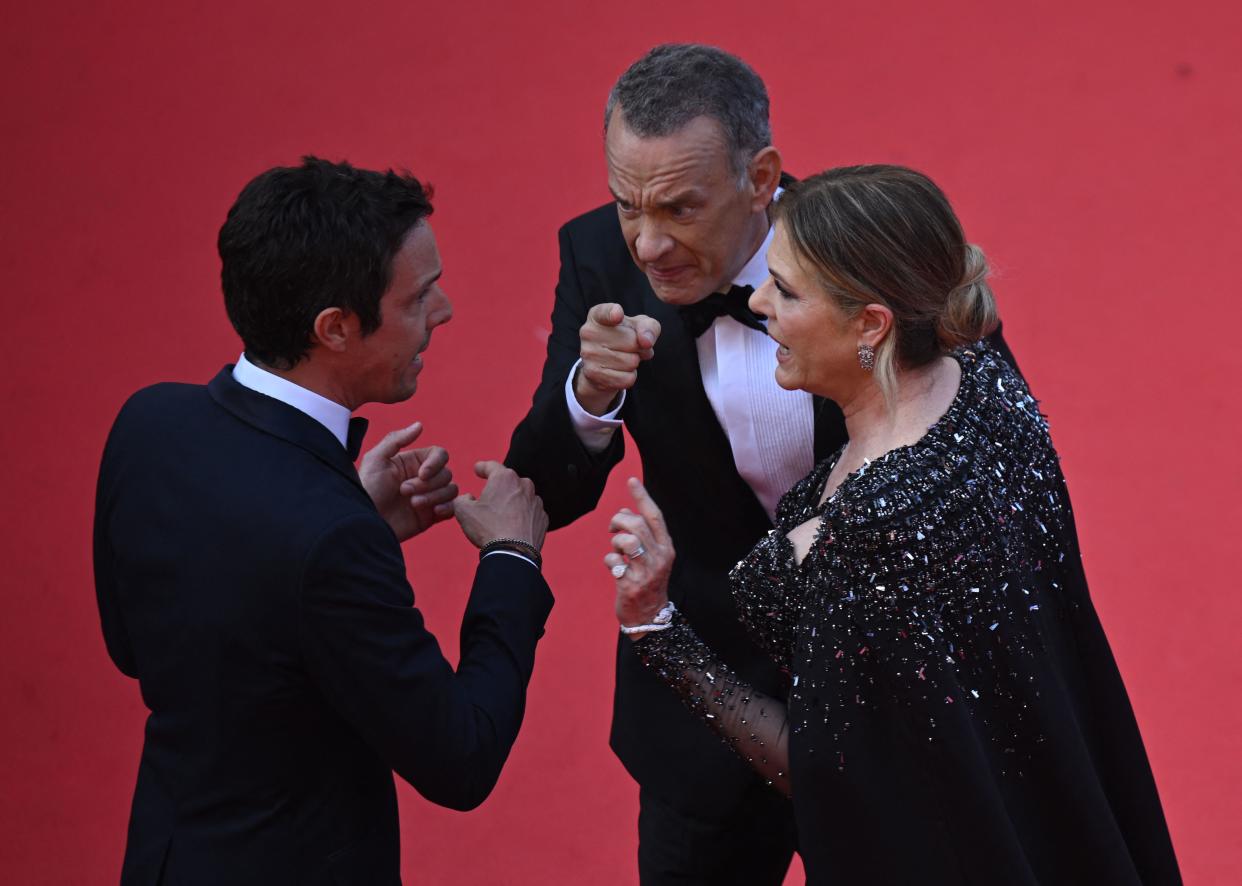 El actor estadounidense Tom Hanks (centro) y la actriz estadounidense Rita Wilson hablan con un miembro del personal cuando llegan a la proyección de la película 