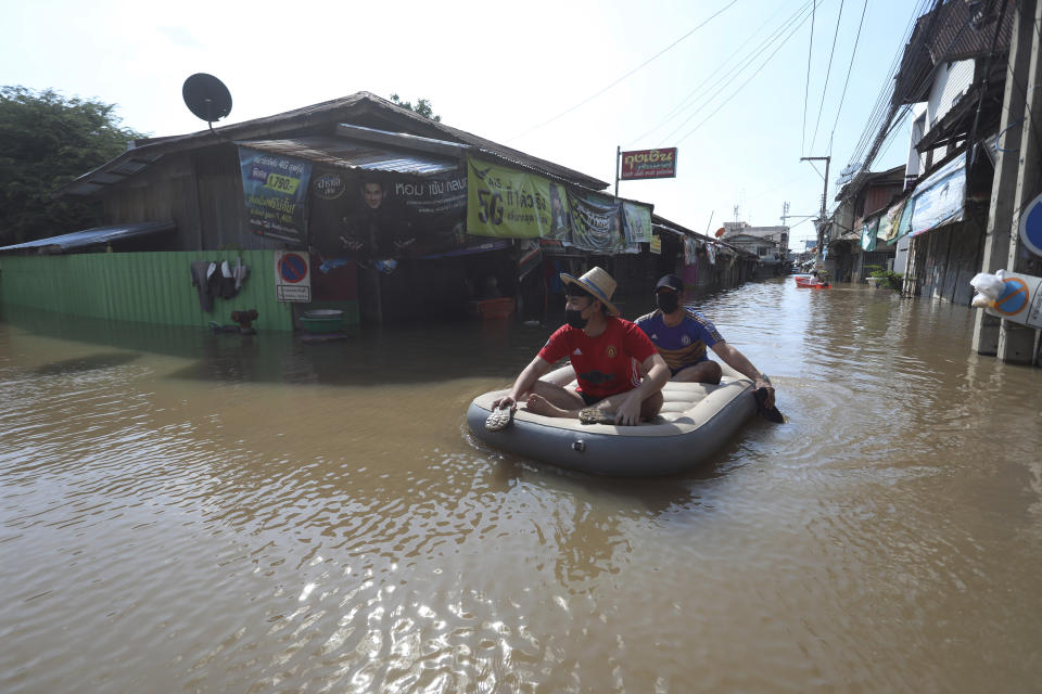 A Thai resident rows his float for his friend on a flooded street in Ayutthaya province, north of Bangkok, Thailand, Tuesday, Oct. 5, 2021. As flood waters continued to inundate areas in northern and central Thailand and were starting to hit low-lying areas in the capital, Thai officials were looking warily ahead Tuesday the possibility of more storms this month, but were optimistic the devastation of a decade ago would not be repeated. (AP Photo/Nathathida Adireksarn)