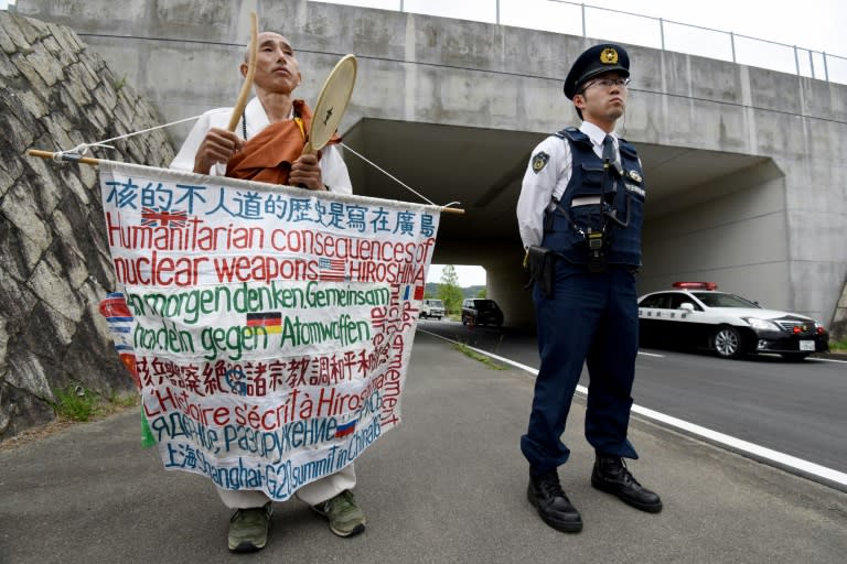 A policeman stands beside a Buddhist monk in front of the International Media Centre in Ise, Mie prefecture, on May 25, 2016