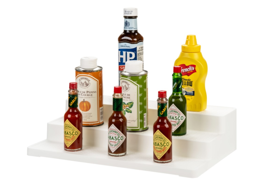various condiments sitting on a BIG W white 3 tier pantry shelf on a white background