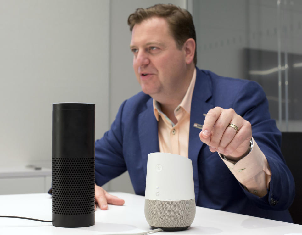 In this June 14, 2018, photo, Gareth Gaston, Executive Vice President and Head of Omnichannel Banking at US Bank, discusses voice assistant banking with an Amazon Echo, left, and a Google Home, right, in New York. Big banks and financial companies have started to offer banking through virtual assistants, Amazon’s Alexa, Apple’s Siri, and Google’s Assistant, in a way that will allow customers to check their balances, pay bills and, in the near future, send money just with their voice. Regional banking giant U.S. Bank is the first bank to be on all three services, Alexa, Siri and Assistant. (AP Photo/Mark Lennihan)