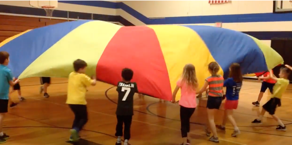 Screenshot of kids playing the parachute game in a gym