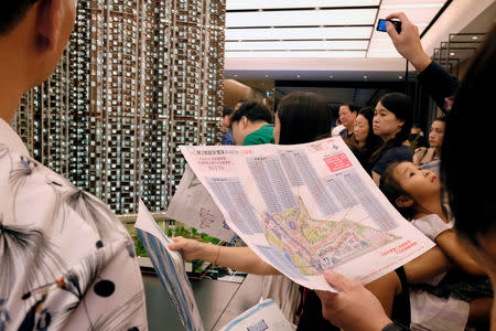 A person checks a price list in front of a model of LP6 property development by Nan Fung Group at a sales centre in Hong Kong, China August 26, 2018. Picture taken August 26, 2018. REUTERS/Bobby Yip