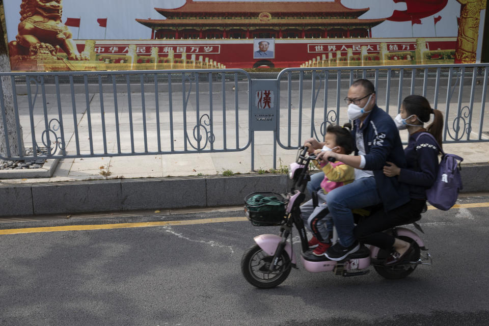 Residents wearing masks against the new coronavirus pass by government propaganda posters featuring Tiananmen Gate in Wuhan in central China's Hubei province on Thursday, April 16, 2020. Top Chinese officials secretly determined they were likely facing a pandemic from a new coronavirus in mid-January, ordering preparations even as they downplayed it in public. (AP Photo/Ng Han Guan)