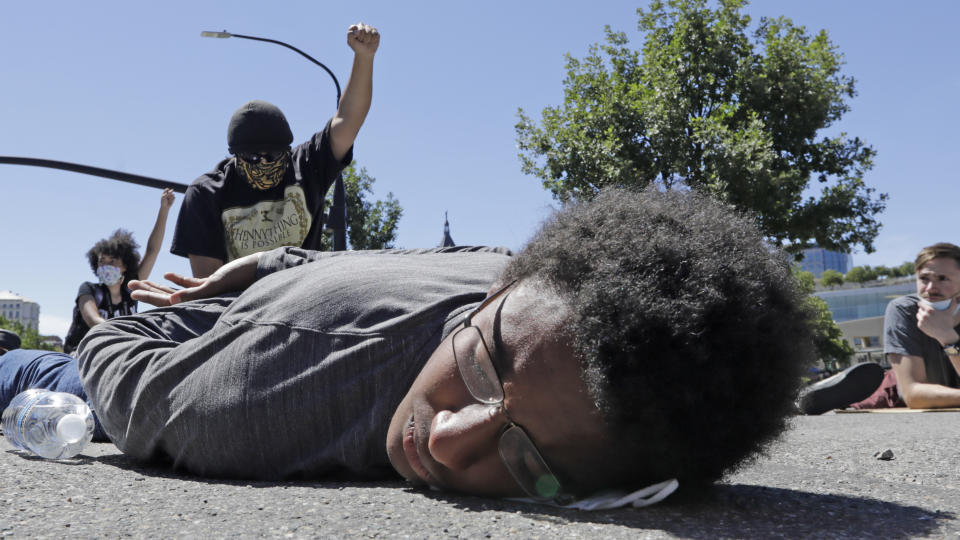 A man lies in the street with his hands behind his back while others demonstrate during a march in Salt Lake City, Friday, June 19, 2020, in Salt Lake City, to mark Juneteenth, the holiday celebrating the day in 1865 that enslaved black people in Galveston, Texas, learned they had been freed from bondage, more than two years after the Emancipation Proclamation. (AP Photo/Rick Bowmer)