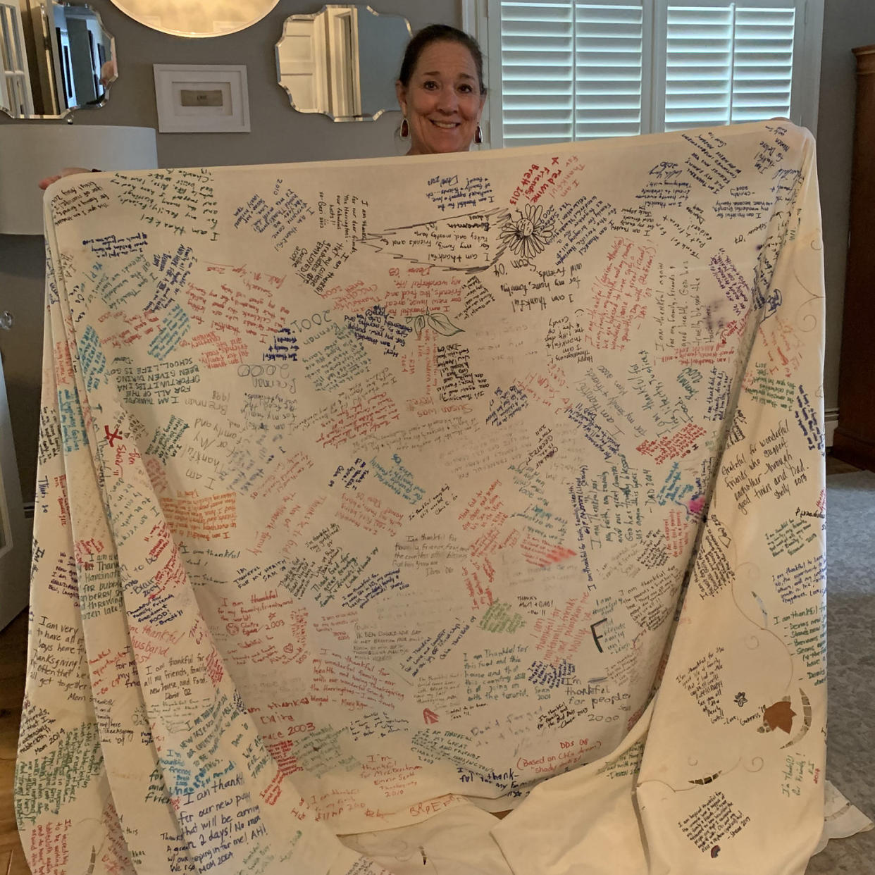 Caroline Harrington holds her Thanksgiving gratitude tablecloth.  (Courtesy Caroline Harrington)