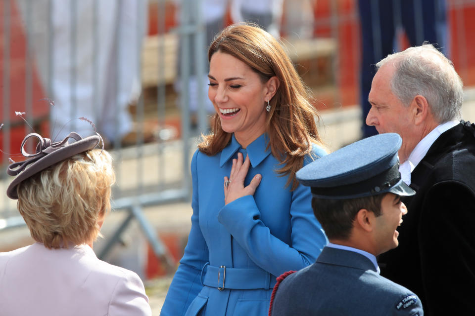 Kate Middleton laughing wearing blue coat. 