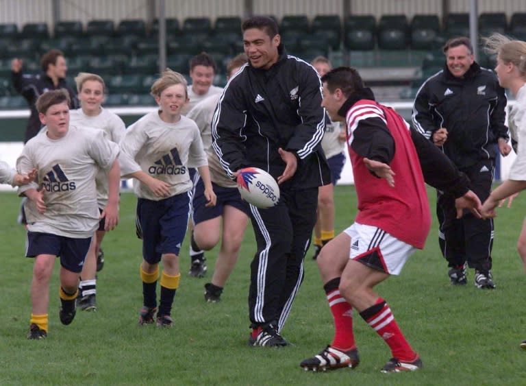 In this photo taken in 1999, New Zealand flanker Dylan Mika, who has died at the age of 45, is chased by school children during a practice session with the All Blacks