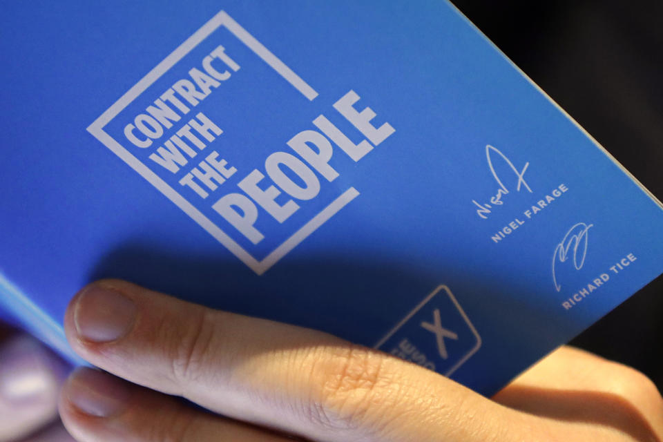 A person in the audience reads Nigel Farage's "Contract with the People", prior to the leader of Britain's Brexit Party's speech at the launch of the party's policies for the General Election campaign, in London, Friday, Nov. 22, 2019. Britain goes to the polls on Dec. 12. (AP Photo/Kirsty Wigglesworth)