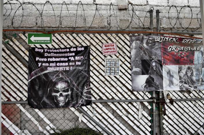Posters of Santa Muerte (Holy Death) read: "I protect delinquents, but robbing me and in my house is your death" at a sanctuary in Santa Maria Cuautepec, Tultitlan, Mexico on February 7, 2016 (AFP Photo/Yuri Cortez)