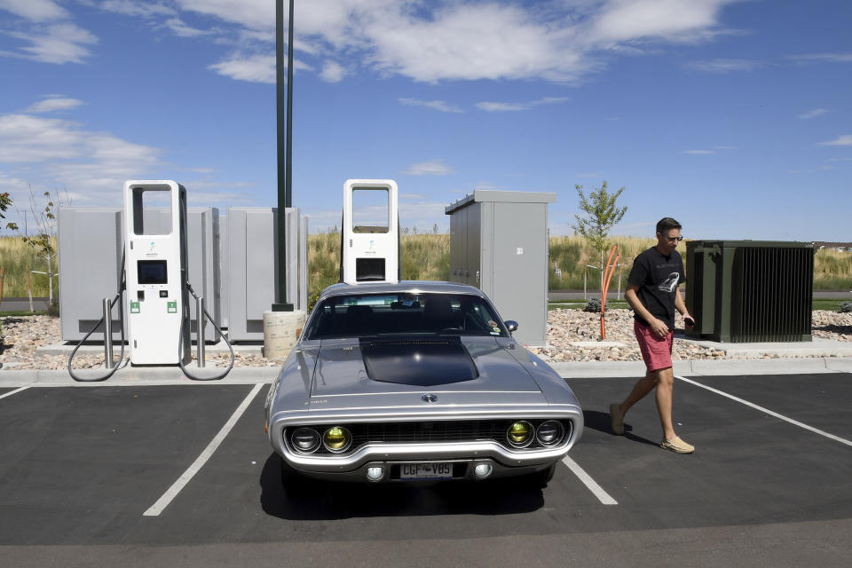 Kevin Erickson walks by his electrified 1972 Plymouth Satellite at a public charging station in Commerce City, Colo., on Sept. 20, 2022. Erickson is part of a small but expanding group of tinkerers, racers, engineers, and entrepreneurs across the country converting vintage cars and trucks into greener, and often much faster, electric vehicles. (AP Photo/Thomas Peipert)
