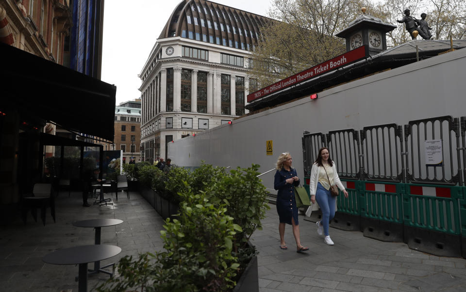 Pedestrians walk past the site of the Official London Theater Ticket booth that normally sells last minute tickets to shows in London, which is currently undergoing renovations in Leicester Square, London, Tuesday, April 20, 2021. (AP Photo/Alastair Grant)