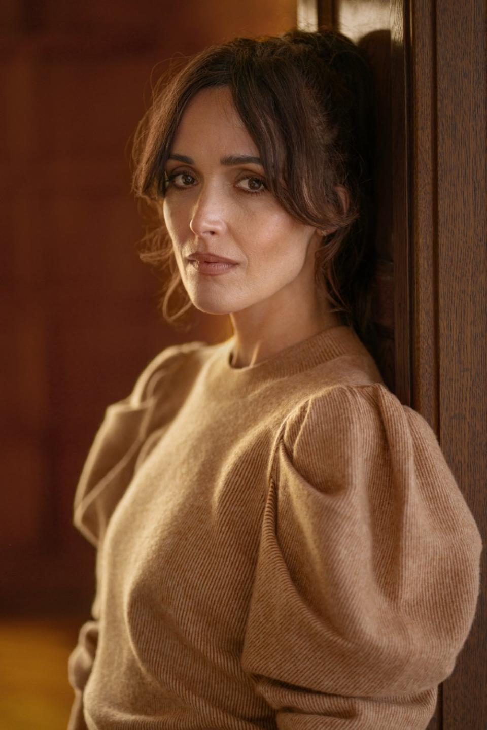 Closeup of Rose Byrne in a sweater with puffed sleeves.