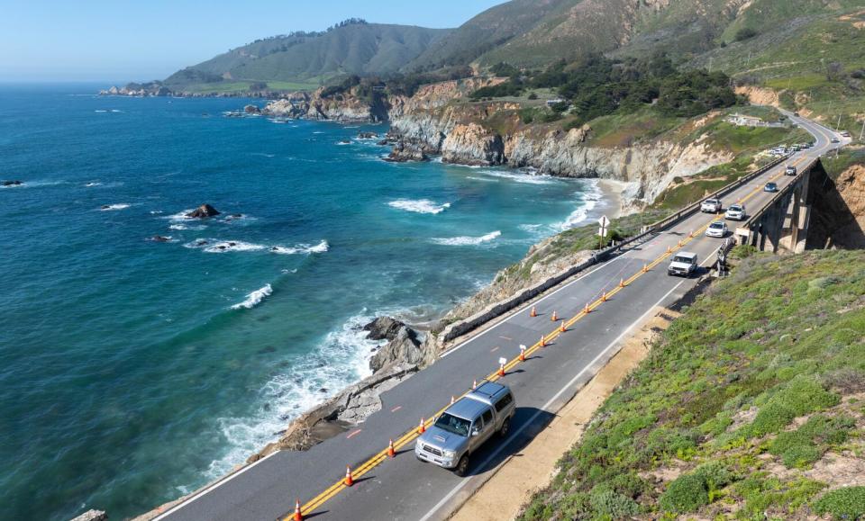 Cars on a road along a coastline.