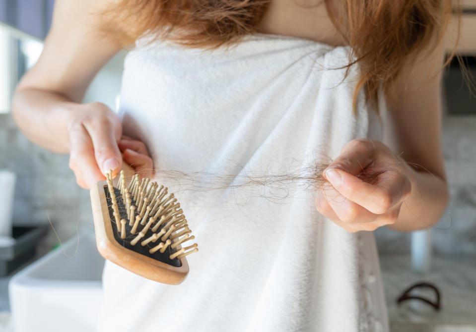 A woman pulling hair out of brush