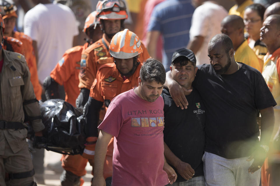 Friends and relatives walk in front of firefighters carrying a body that was found under the debris after a mudslide in Boa Esperanca or "Good Hope" shantytown in Niteroi, Brazil, Saturday, Nov. 10, 2018. Several people were killed and others injured in a mudslide near Rio de Janeiro on Saturday, Brazilian authorities said. (AP Photo/Leo Correa)