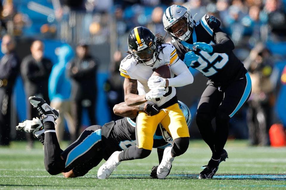 Carolina Panthers safety Xavier Woods (25) and Carolina Panthers cornerback Jaycee Horn (8) tackle Pittsburgh Steelers wide receiver Diontae Johnson (18) during a game at Bank of America Stadium in Charlotte, N.C., Sunday, Dec. 18, 2022.
