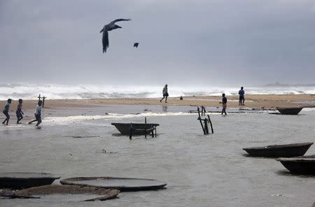 Fishermen walk along the shore at Ganjam district in Odisha October 11, 2014. REUTERS/Stringer