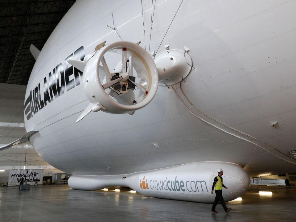 the exterior of the Airlander 10 in a hangar with someone walking by