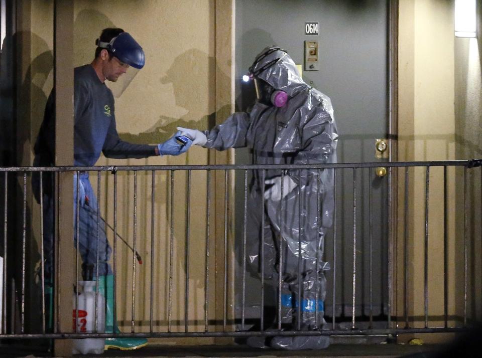 A worker in a hazardous material suit hands a device over to a co-worker after stepping out of an apartment unit where a man diagnosed with the Ebola virus was staying in Dallas, Texas, October 4, 2014. (REUTERS/Jim Young)