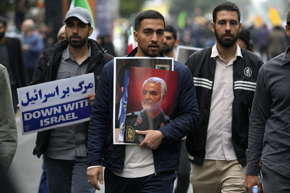 Iranian demonstrators hold a poster of the late Iranian Revolutionary Guard Gen. Qassem Soleimani, who was killed in a U.S. drone attack in 2020, and an anti-Israeli placard during a rally in front of the former U.S. Embassy in Tehran, Iran, marking 44th anniversary of the seizure of the embassy by militant Iranian students, Saturday, Nov. 4, 2023. (AP Photo/Vahid Salemi)