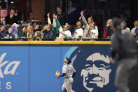 Fans seated near the left field wall point skyward as they and Texas Rangers left fielder Jason Martin follow the path of the solo home run by Seattle Mariners' Jacob Nottingham during the third inning of a baseball game Thursday, May 27, 2021, in Seattle. (AP Photo/Elaine Thompson)