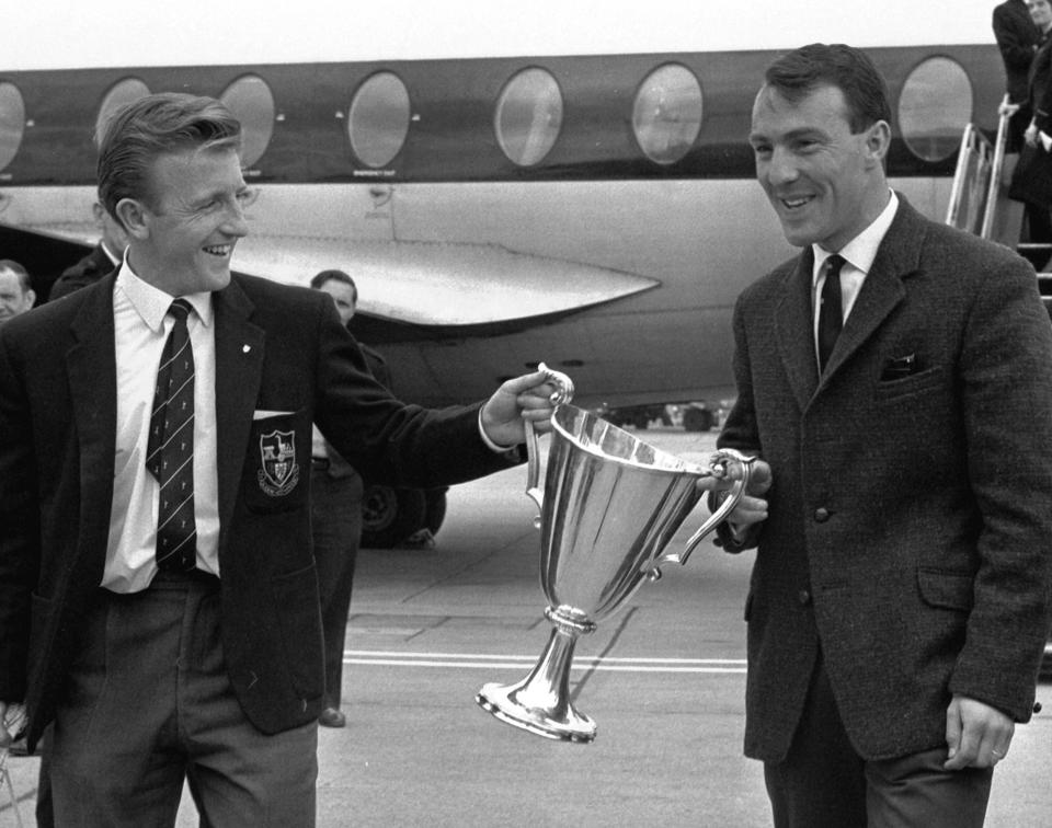 FILE - In this May 16, 1963 file photo, Tottenham Hotspur forwards Jimmy Greaves, right, and Terry Dyson carry the European Cup Winners Cup, at London's Heathrow airport. Spurs defeated Athletico Madrid 5-1 in the European Cup Winners Cup Final becoming the first British club to win the tournament. Jimmy Greaves, one of England’s greatest goal-scorers who was prolific for Tottenham, Chelsea and AC Milan has died. He was 81. With 266 goals in 379 appearances, Greaves was the all-time record scorer for Tottenham, which announced his death on Sunday, Sept. 19, 2021. (AP Photo/Victor Boynton, File)