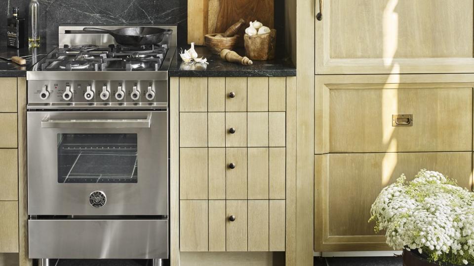 a galley kitchen with warm wood grain cabinets and a stainless steel range
