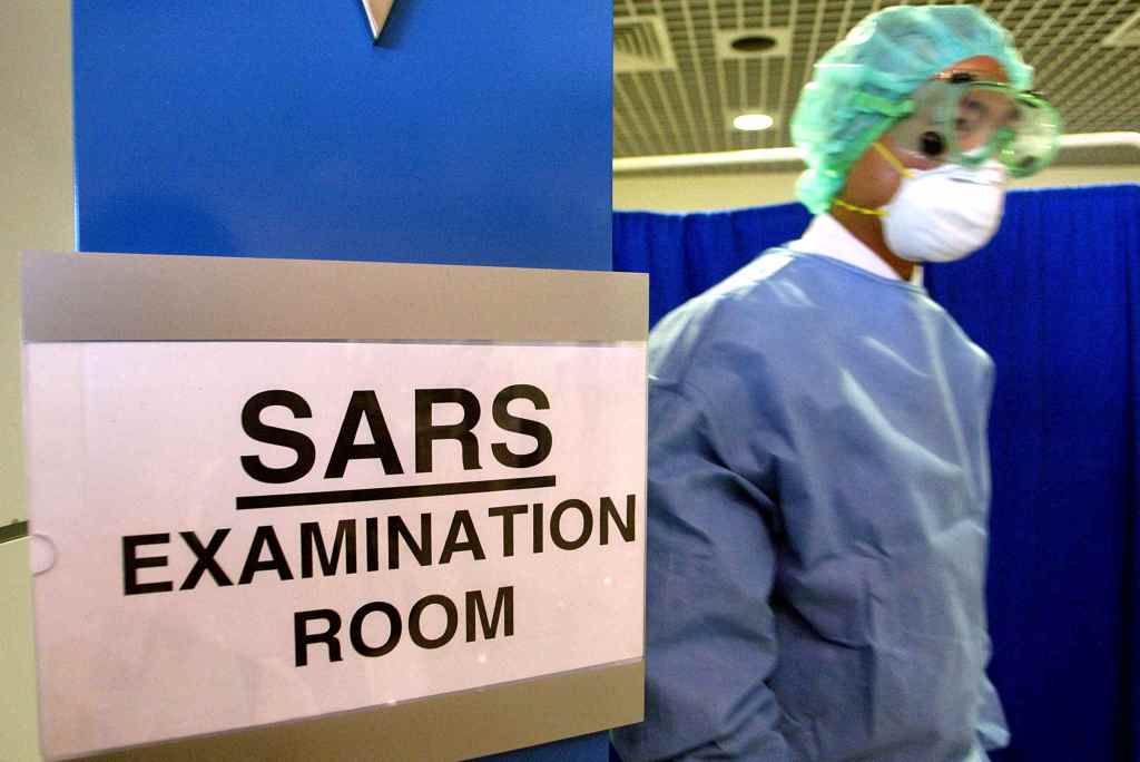 TOPSHOT - A doctor dressed in full protective gear walks out from an examination room for Severe Acute Respiratory Syndrome (SARS) near arrival gates at the KL International Airport in Sepang 24 April 2003. Malaysia is exploring the establishment of an ASEAN centre for control disease centre to combat the deadly SARS virus, Malaysia's Health Minister Chua Jui Meng said. AFP PHOTO / Jimin LAI (Photo by JIMIN LAI / AFP) (Photo by JIMIN LAI/AFP via Getty Images)