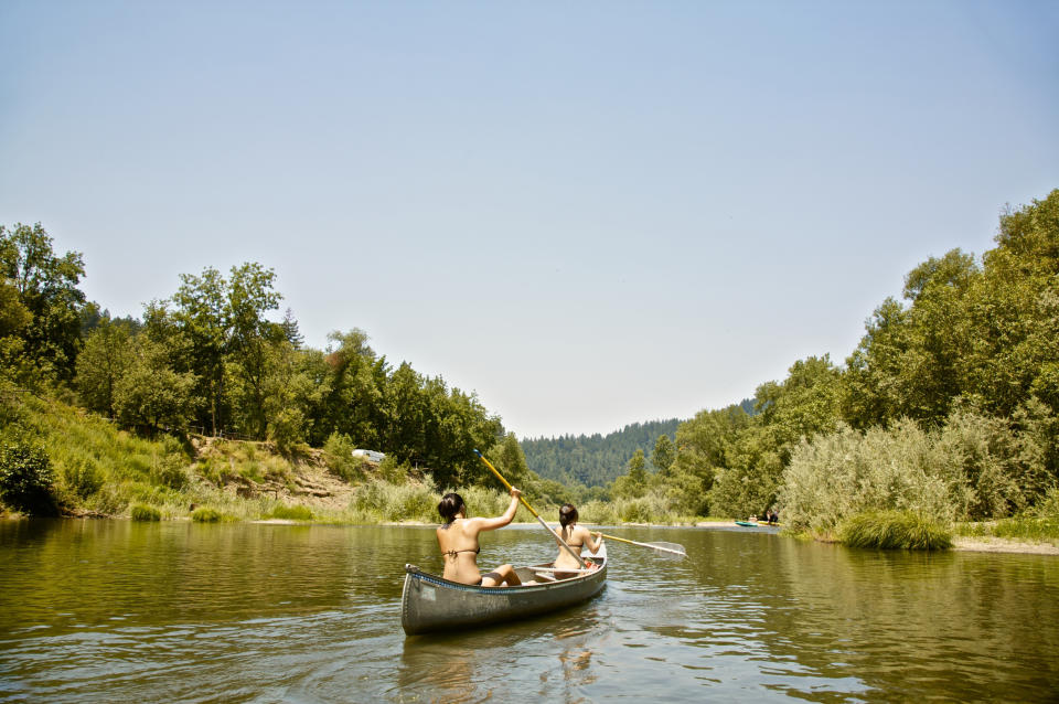 Rear view of women rowing canoe in rural lake.