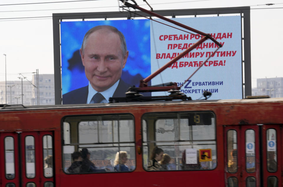 People look through the tram windows as they pass a big screen showing Russian President Vladimir Putin and reading: "Happy birthday to President Vladimir Putin from the Serb brethren!", in Belgrade, Serbia, Friday, Oct. 7, 2022. The posters are signed by a Pro-Russian right-wing group. Putin remains popular in Serbia despite the attack on Ukraine, and many in the Balkan country believe that the Russian president was provoked by the West into launching the invasion. (AP Photo/Darko Vojinovic)