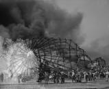 <p>Clouds of smoke rise from the twisted metal frame of the German airship Hindenburg as rescue workers arrive to look for possible survivors, May 6, 1937, in Lakehurst, N.J. The Hindenburg exploded as it was mooring at the Lakehurst Naval Air Station. (AP Photo) </p>