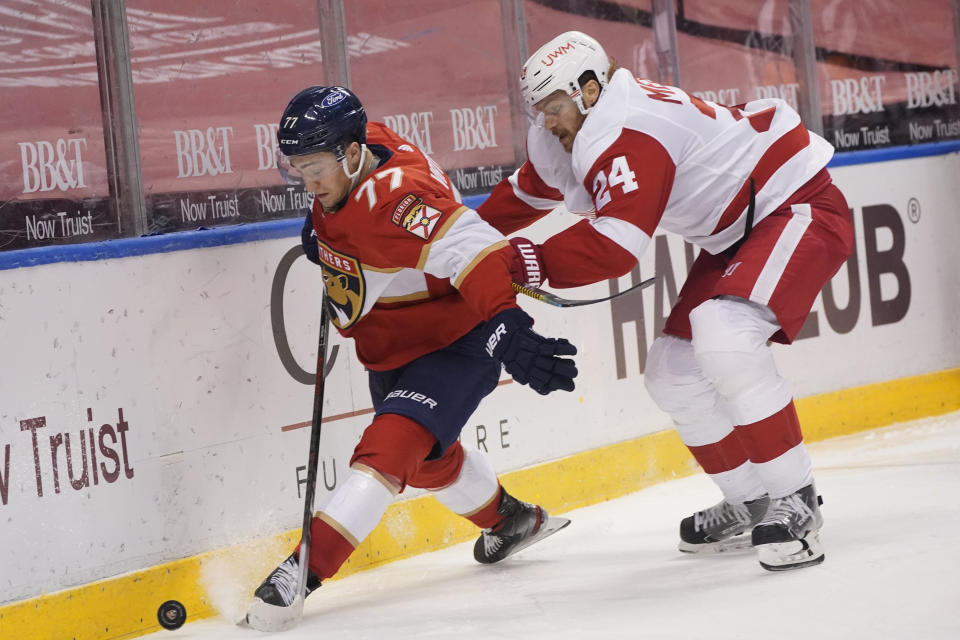 Florida Panthers center Frank Vatrano (77) and Detroit Red Wings defenseman Jon Merrill (24) battle for the puck during the second period of an NHL hockey game, Sunday, Feb. 7, 2021, in Sunrise, Fla. (AP Photo/Wilfredo Lee)