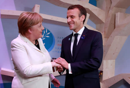 German Chancellor Angela Merkel and French President Emmanuel Macron hold hands after leaving books at the peace library at the Paris Peace Forum as part of the commemoration ceremony for Armistice Day, 100 years after the end of the First World War, in Paris, France, November 11, 2018. REUTERS/Gonzalo Fuentes/Pool