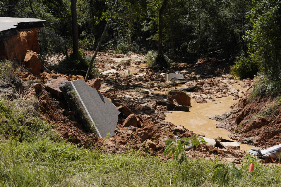 Vehicle debris are mixed with torn road sections of Mississippi Highway 26, in the Crossroads community, Tuesday, Aug. 31, 2021. Two people were killed and at least 10 others were injured when seven vehicles plunged, one after another, into the deep hole on the dark rural two-lane highway, which collapsed after Hurricane Ida blew through Mississippi. (AP Photo/Rogelio V. Solis)